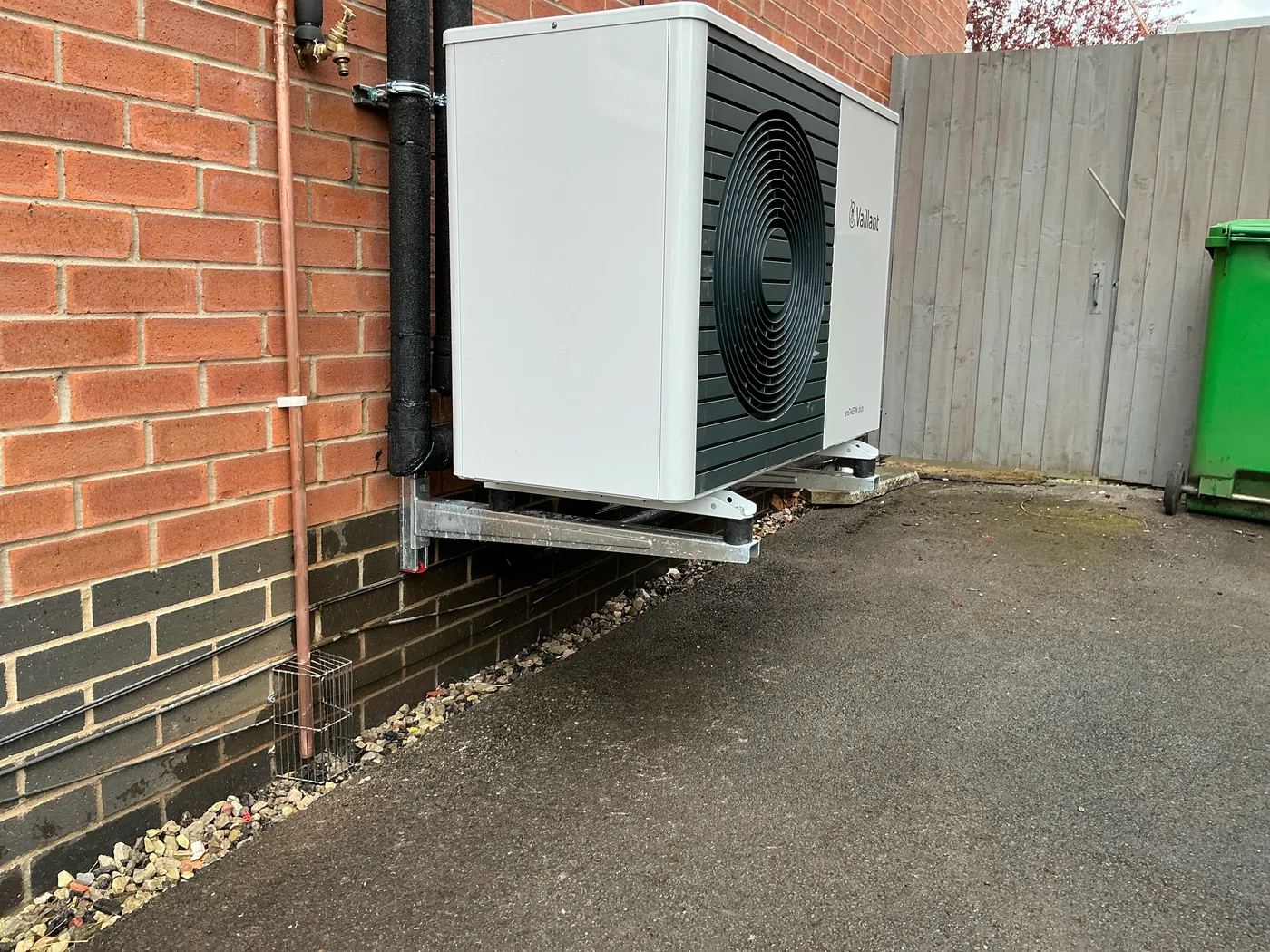 Vaillant heat pump installed on wall brackets beside the driveway